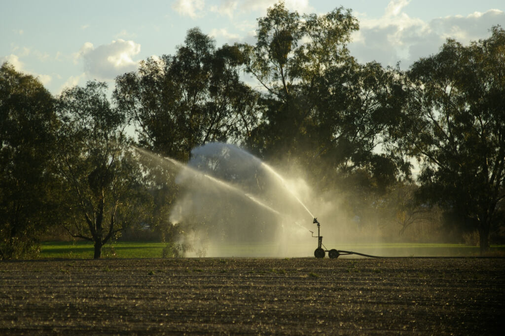 an industrial large water sprinkler spraying water on a farm in rural New South Wales, Australia