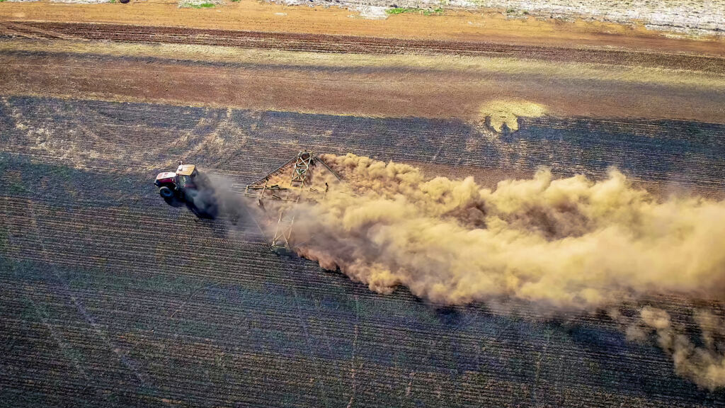 Aerial views of a tractor turning over soil in a field in Central Victoria